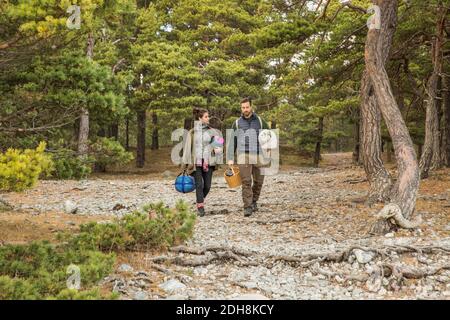 Couple transportant des sacs de couchage et un panier en forêt Banque D'Images