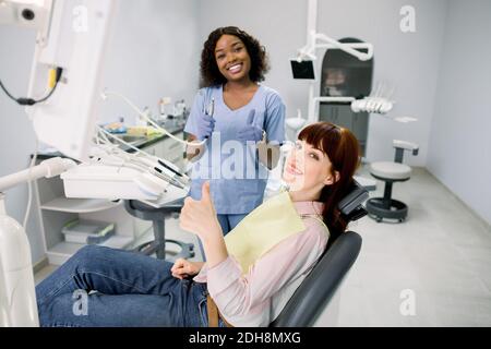 Concept de prévention des dents et des caries en bonne santé. Jeune femme européenne à la chaise du dentiste pendant un examen et un traitement dentaires, montrant le pouce vers le haut Banque D'Images