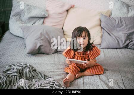Portrait d'une fille atteinte du syndrome de Down en utilisant une tablette numérique pendant qu'elle est assise sur le canapé à la maison Banque D'Images