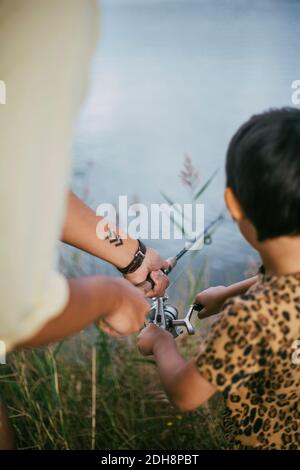 Main de père et fille de pêche dans le lac pendant été Banque D'Images