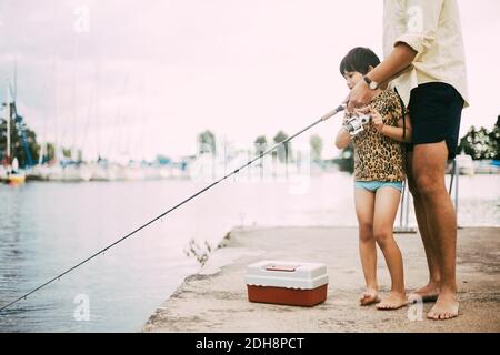 Basse section de père et fille pêche dans le lac pendant été Banque D'Images