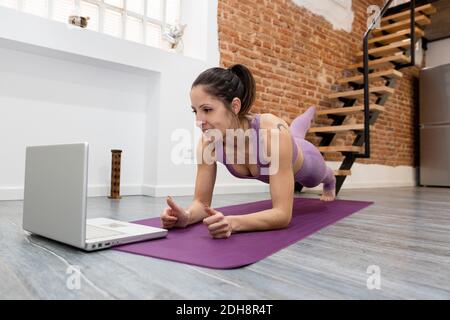 Smiley sports fille entraînement à la maison prenant des cours en ligne de son ordinateur portable. Concept de santé, de maison et de bien-être. Espace pour le texte. Banque D'Images