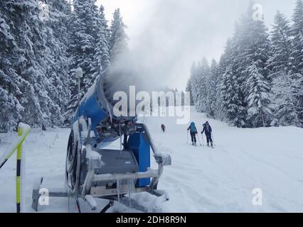 Garmisch Partenkirchen, Allemagne. 10 décembre 2020. Les amateurs de ski passent devant un canon à neige. Pas de plaisir sur les pistes, pas d'après-ski - mais dans certains endroits, il y a des couvre-feux et la frontière avec l'Autriche est pratiquement fermée : la saison sera difficile pour les amateurs de sports d'hiver. Credit: Angelika Warmuth/dpa/Alamy Live News Banque D'Images