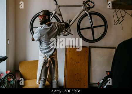 Vue arrière de la bicyclette de réparation de propriétaire masculin dans l'atelier Banque D'Images