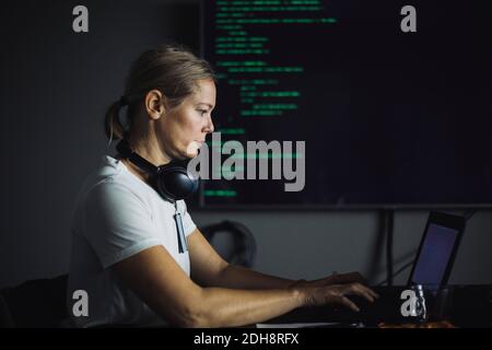Vue latérale du PROFESSIONNEL DE L'INFORMATIQUE travaillant sur un ordinateur portable au bureau Banque D'Images