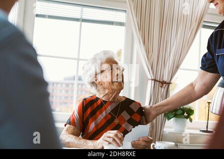 Bonne femme âgée regardant la gardienne tout en jouant aux cartes avec famille Banque D'Images