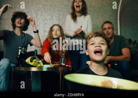 Un garçon criait pendant que la famille applaudisse lors d'un événement sportif la nuit Banque D'Images