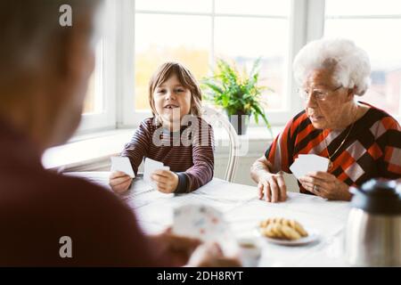 Joyeux garçon jouant des cartes avec de grands-parents à la maison Banque D'Images