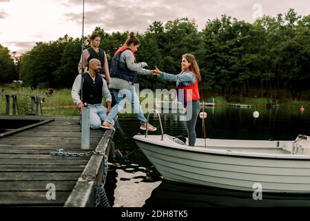 Les parents regardent la fille tenant la main de la sœur tout en se tenant debout bateau sur le lac Banque D'Images