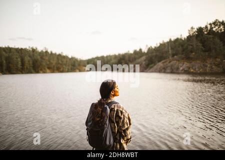 Vue arrière de la femme avec sac à dos debout contre le lac dans forêt Banque D'Images