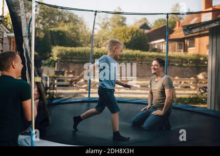 Père et fils souriants jouant au trampoline pendant le week-end Banque D'Images