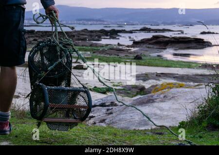 Une vue détaillée du pêcheur avec des pièges à crabe qui se promets à pied la plage à marée basse pour aller au travail Banque D'Images