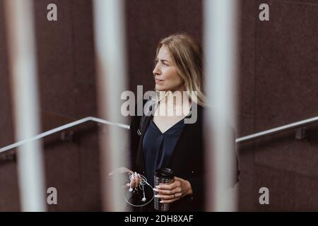 Femme d'affaires contemplant une tasse de café qui regarde loin dans la ville Banque D'Images