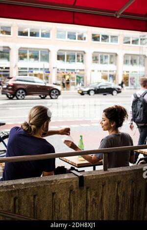 Homme prenant des tissus de femme en étant assis au café-terrasse en face de la rue de la ville Banque D'Images