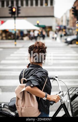 Femme avec vélo debout sur le passage de zébra dans la ville Banque D'Images