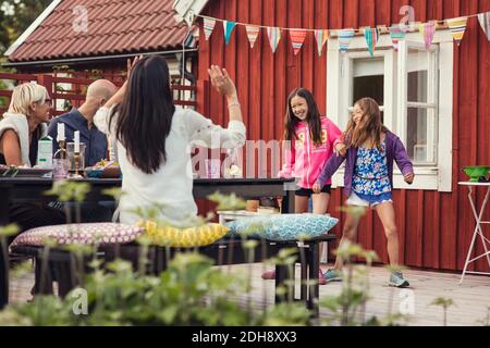 Famille et amis heureux regardant les filles danser dans la cour arrière pendant la fête dans le jardin Banque D'Images