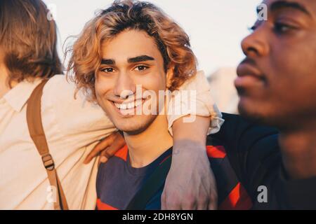 Portrait d'un jeune homme souriant avec des amis masculins debout ville Banque D'Images