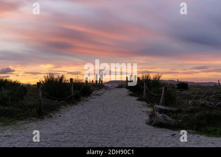 Un chemin de sable et un accès à la plage menant à travers les dunes sous un lever de soleil coloré ciel matin Banque D'Images