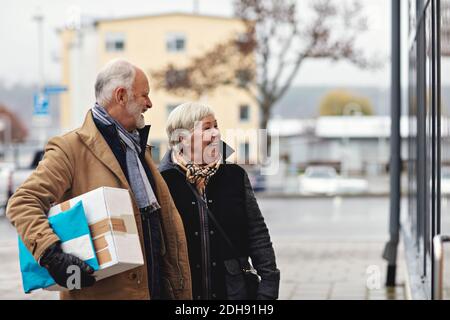 Couple senior souriant avec forfait en ville en hiver Banque D'Images