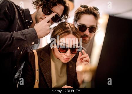 Des amis souriants qui essaient des lunettes tendance en magasin Banque D'Images