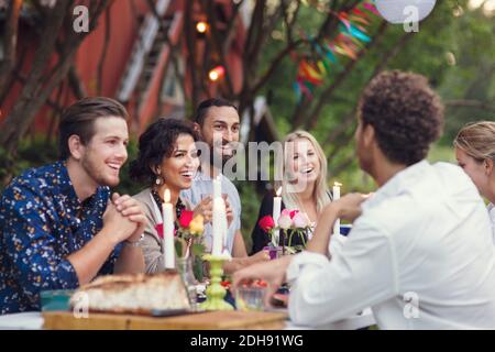 Des amis heureux communiquant tout en dégustant un repas dans le jardin Banque D'Images