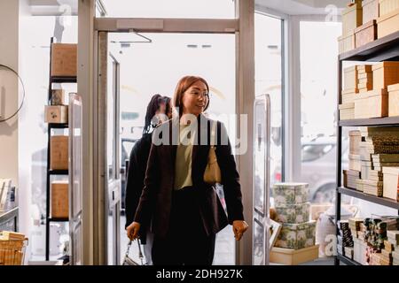 Des amies souriantes entrent dans le magasin Banque D'Images