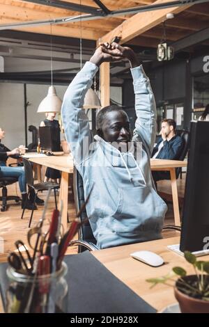 Un programmeur informatique souriant s'étirant sur le lieu de travail Banque D'Images