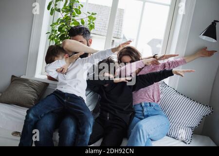 Une famille joyeuse qui fait du dab tout en étant assis sur un canapé dans la salle de séjour chambre à la maison Banque D'Images