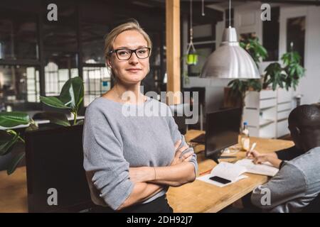 Portrait d'un freelancer confiant avec les bras croisés sur le lieu de travail Banque D'Images