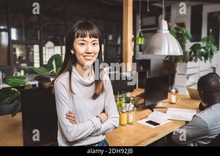 Portrait d'une femme d'affaires souriante avec les bras croisés sur le lieu de travail Banque D'Images