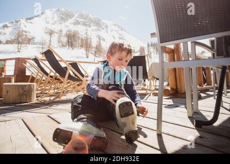 Garçon portant des chaussures de ski près du siège sur le plancher Banque D'Images