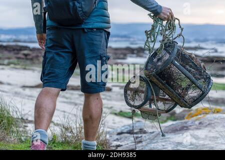 Une vue détaillée du pêcheur avec des pièges à crabe qui se promets à pied la plage à marée basse pour aller au travail Banque D'Images