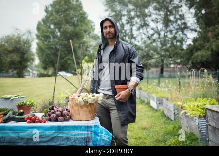 Portrait d'un homme adulte moyen debout près de légumes fraîchement récoltés sur table dans le jardin urbain Banque D'Images