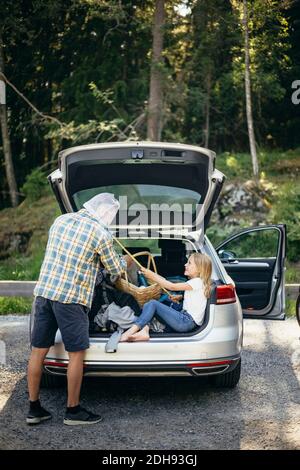 Vue latérale de la fille couvrant la face du père avec filet de pêche assis dans le coffre Banque D'Images