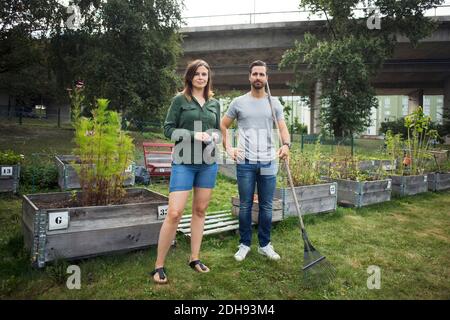 Portrait complet d'un couple adulte moyen avec outils de jardinage au jardin urbain Banque D'Images