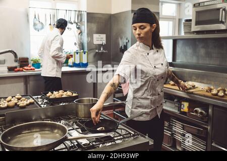 Chefs hommes et femmes préparant des plats dans une cuisine commerciale Banque D'Images