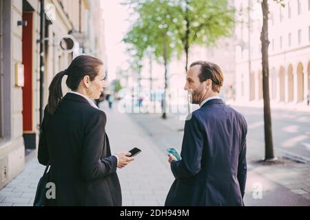 Vue arrière des personnes en voyage d'affaires sur le trottoir Banque D'Images