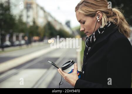 Vue du profil d'une femme d'affaires de taille moyenne adulte utilisant un téléphone mobile sur rue de la ville Banque D'Images