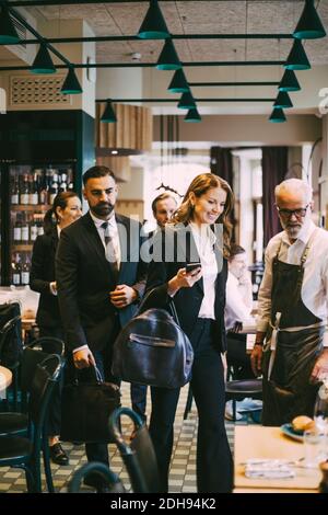 Femme d'affaires souriante avec collègues au restaurant Banque D'Images