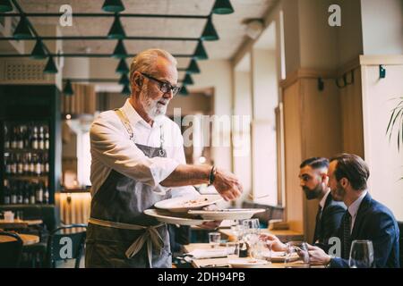 Un serveur tient des assiettes au restaurant Banque D'Images