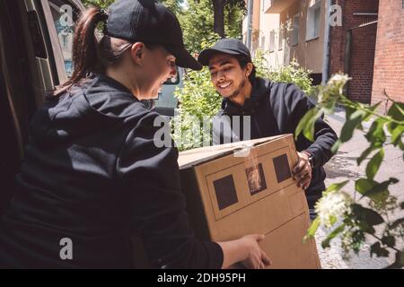 Des collègues souriants qui tiennent la boîte en carton près du camion Banque D'Images