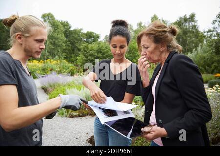 Architectes de jardin avec des plans et tablette numérique discutant dans le jardin Banque D'Images