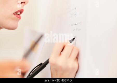 Portrait of businesswoman writing on whiteboard in office Banque D'Images