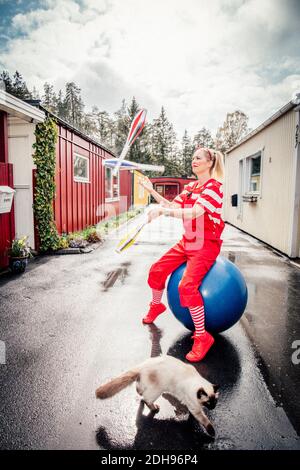 Femme avec des épingles de jonglage assis sur le ballon de fitness sur la route Banque D'Images