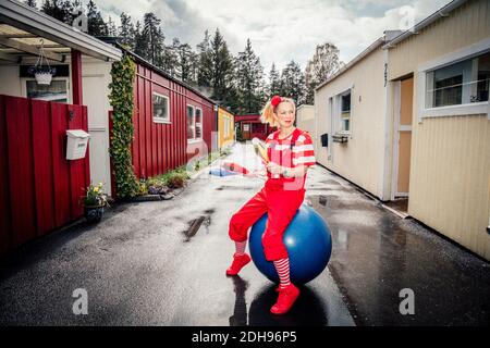 Femme avec des épingles de jonglage regardant loin tout en étant assise sur la forme physique bille Banque D'Images