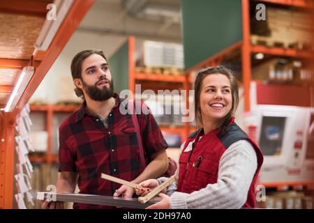 Bonne vendeuse qui regarde loin en se tenant avec un client masculin magasin de matériel Banque D'Images