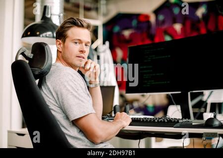 Portrait d'un programmeur d'ordinateur de sexe masculin assis au bureau Banque D'Images