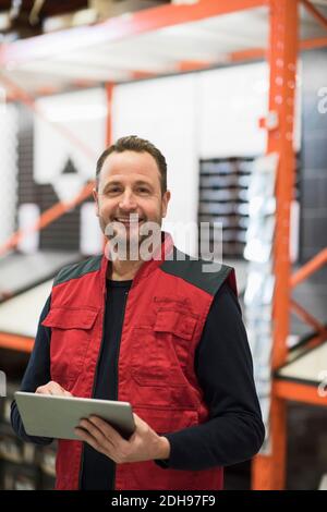 Portrait d'un vendeur heureux tenant une tablette numérique debout magasin de matériel Banque D'Images