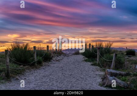 Un chemin de sable et un accès à la plage menant à travers les dunes sous un lever de soleil coloré ciel matin Banque D'Images