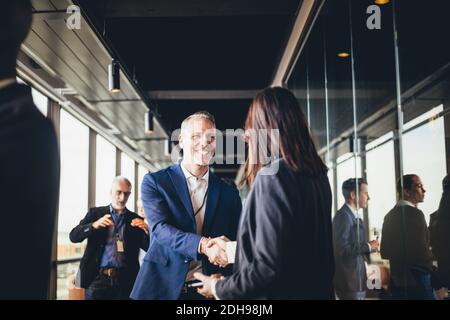 Homme souriant entrepreneur serrer la main avec femme d'affaires sur le lieu de travail Banque D'Images